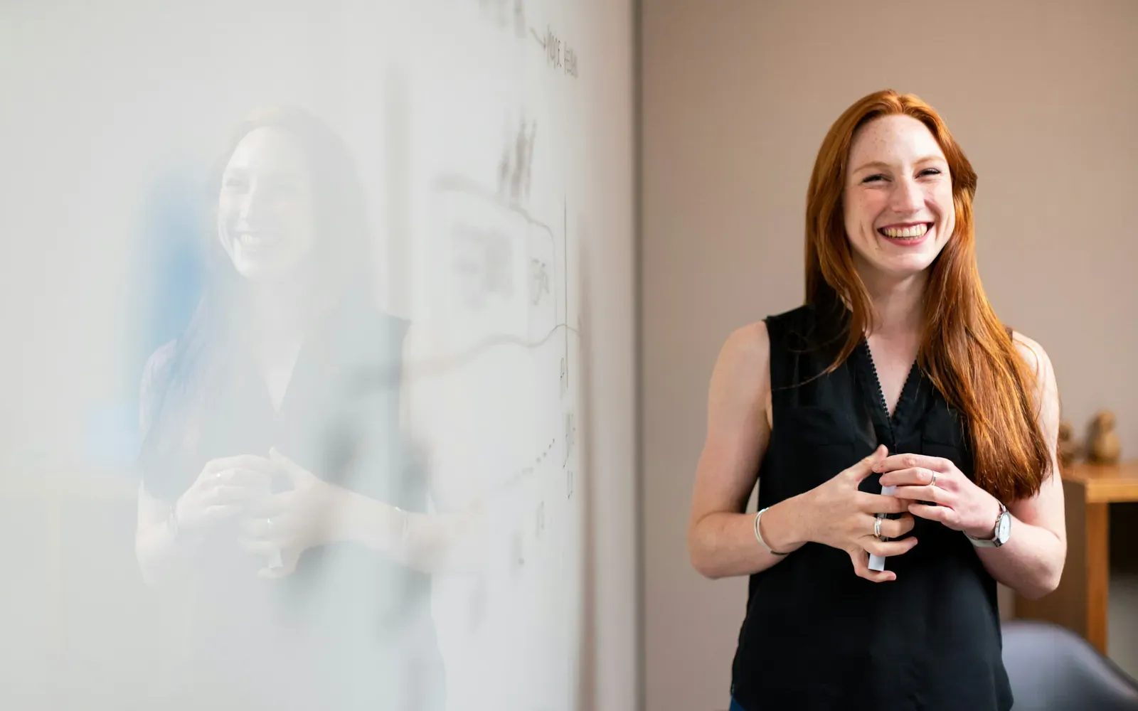 Smiling professional presenting ideas at a whiteboard, representing the expertise behind an EB-1A extraordinary ability green card petition.