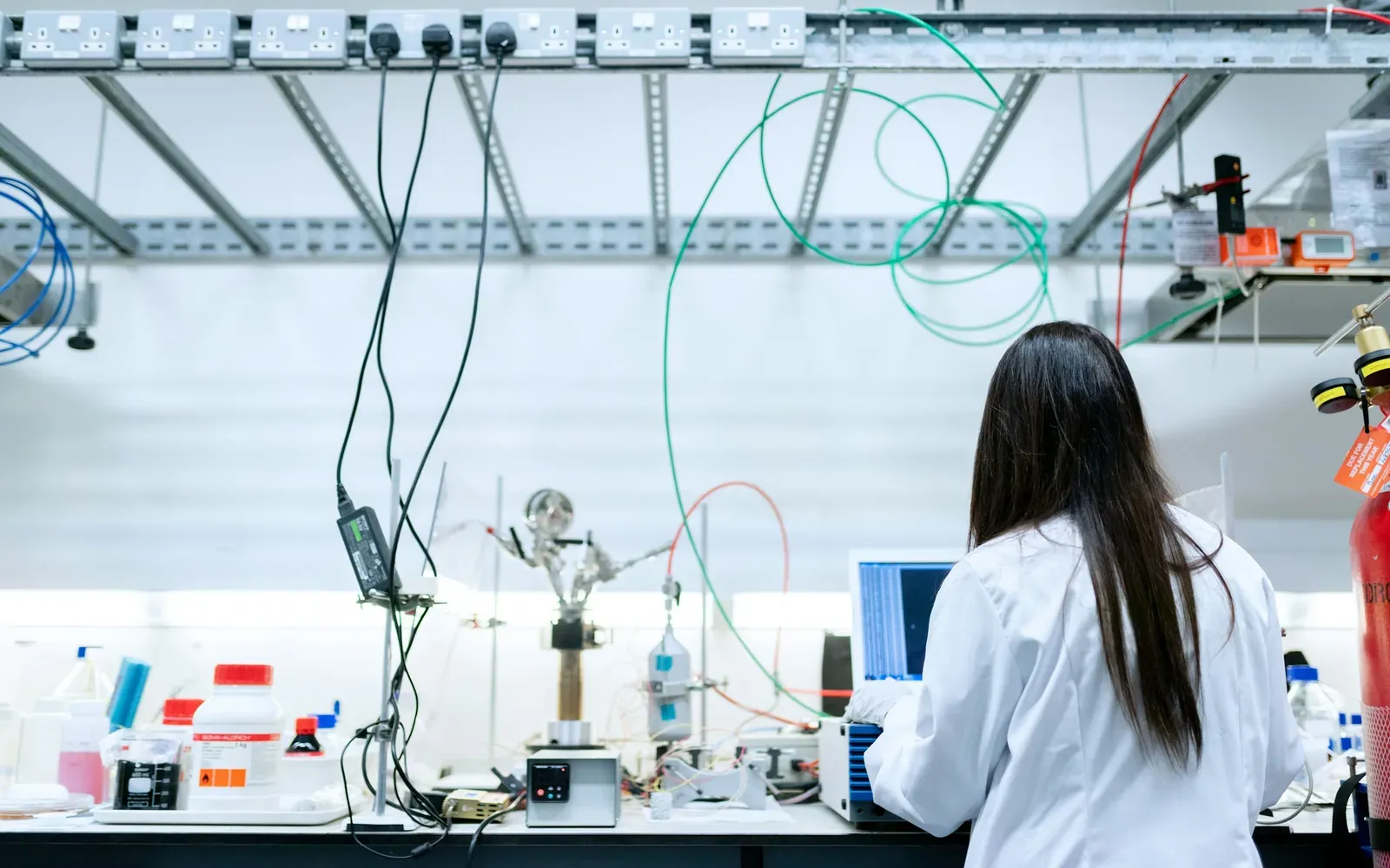 Scientist in a lab coat working at a computer in a research laboratory, representing an EB-2 National Interest Waiver petition.