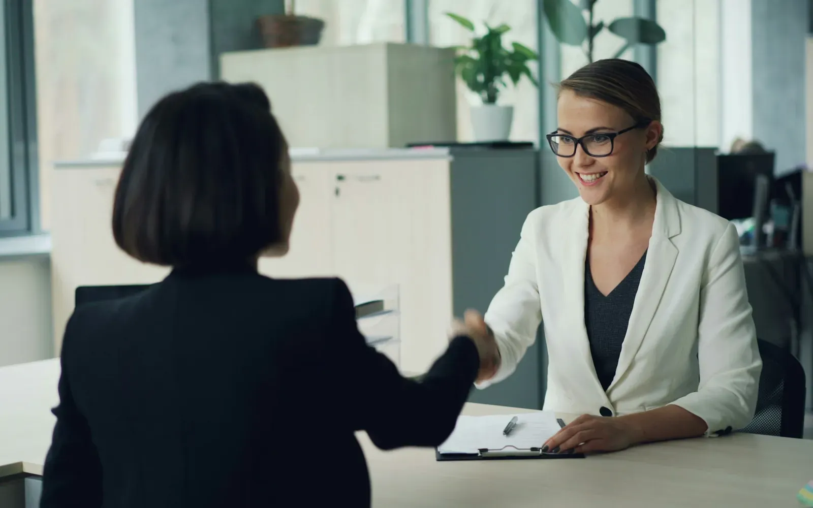 Employer shaking hands with a candidate across a desk, representing employer-sponsored PERM labor certification for a green card.