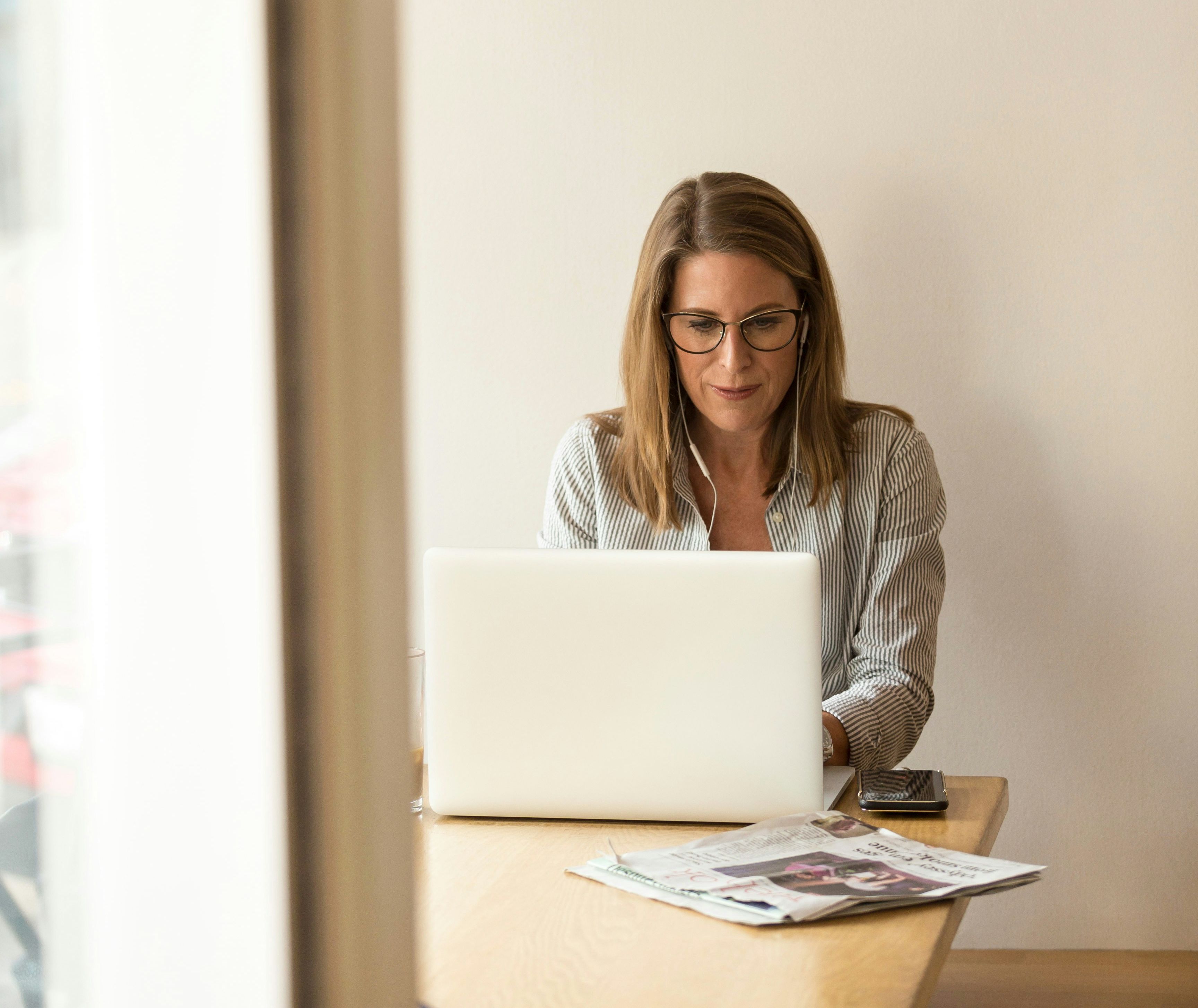 Woman at a wooden table checking dates on her laptop, representing how to read the monthly Visa Bulletin and track a green card priority date.