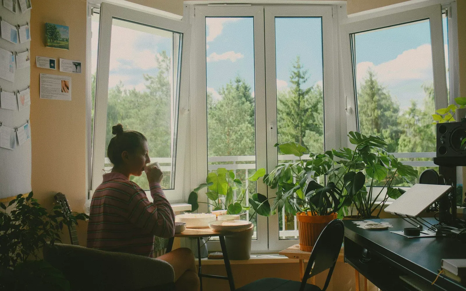 Woman drinking coffee by an open window at home, waiting for a USCIS case decision during 2026 processing delays.